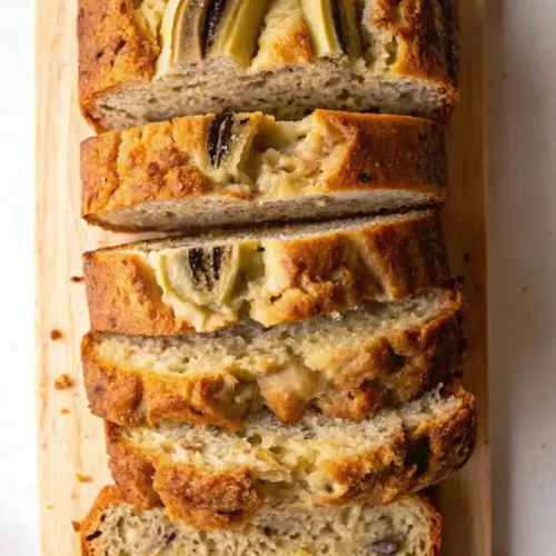 Ingredients for 4 ingredient banana bread including bananas, eggs, flour, and sugar on a white marble countertop.