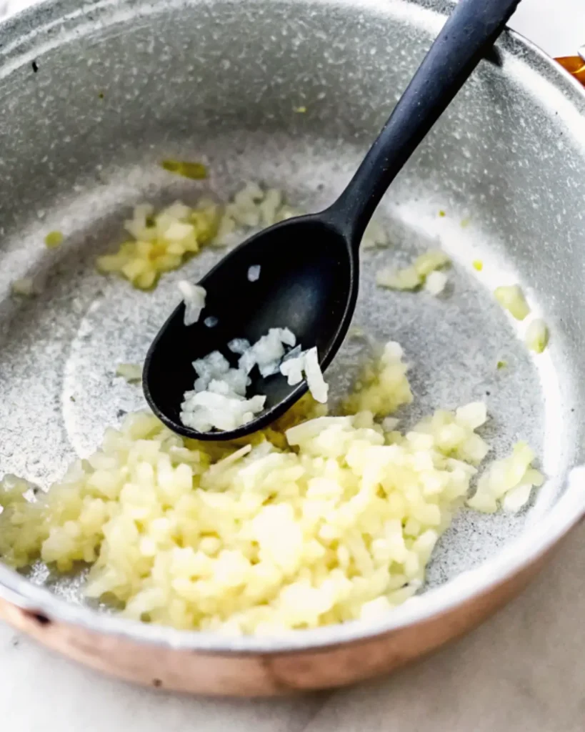 Sautéing onions and garlic for the baked beans recipe in a skillet