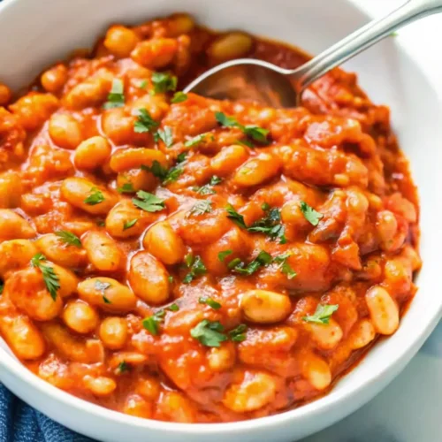 A bowl of baked beans recipe garnished with parsley