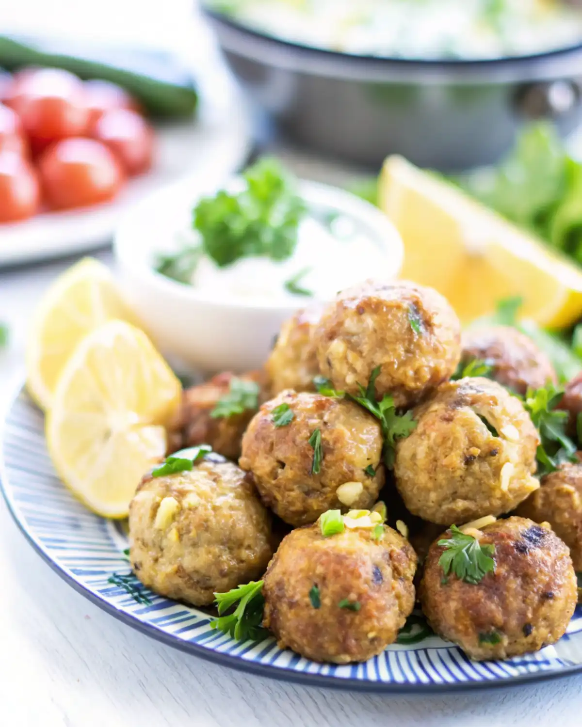 Greek Turkey Meatballs Juicy Greek turkey meatballs served with lemon wedges and fresh parsley on a blue-rimmed plate.